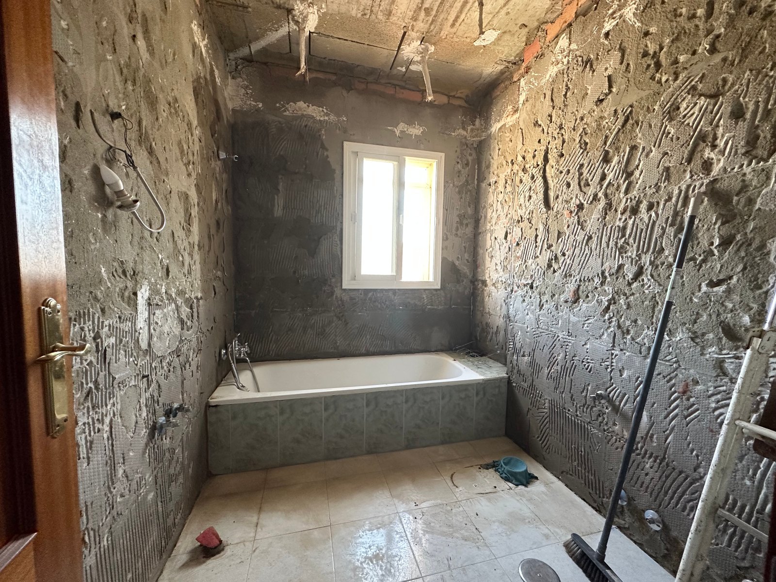 Baño antes de la reforma con azulejos antiguos y bañera