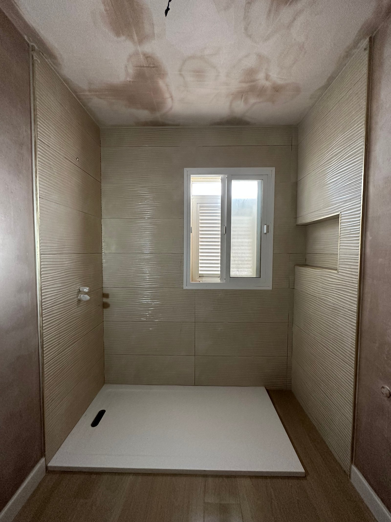 Azulejos texturados beige colocados antes de los sanitarios