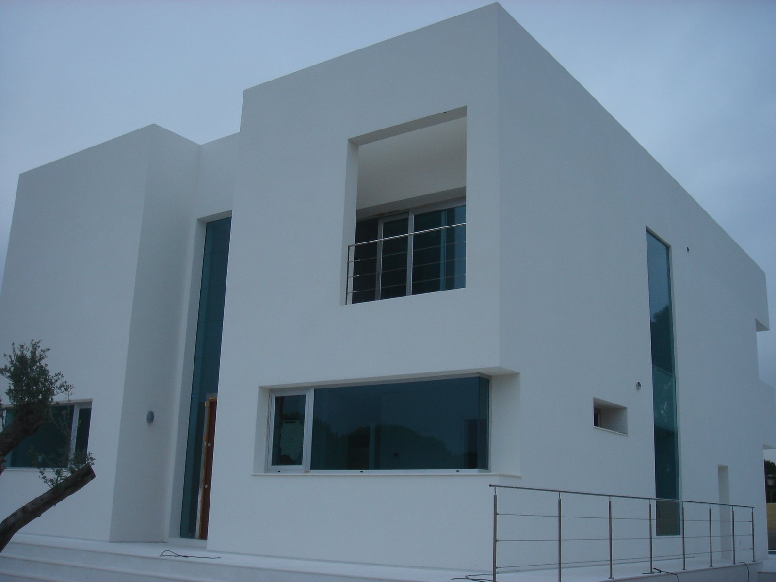 Fachada blanca con grandes ventanales del chalet El Pinar